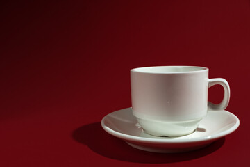 Poster - Closeup shot of a white cup and saucer isolated on red background