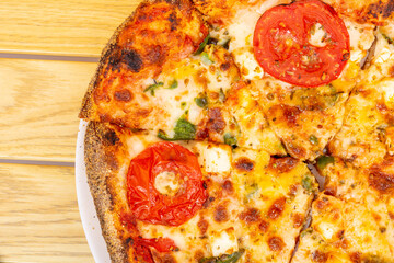 Sticker - Top view of a pizza with tomatoes and greens on a wooden table