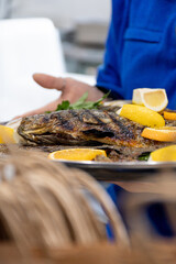 Sticker - Serving of delicious grilled fish with greens and lemons in a fish market in Italy