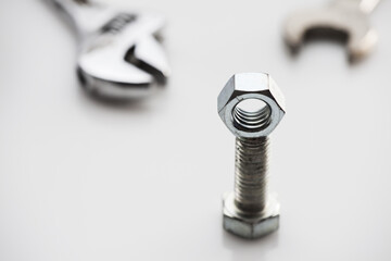 Poster - Close-up shot of silver nuts and bolts on a blurred white table background