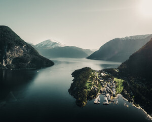 Wall Mural - View of a bay with a small port town and snowy mountains in the background