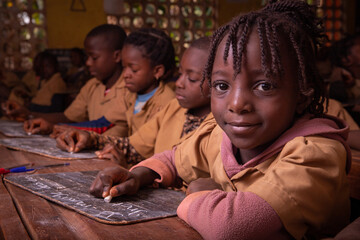 students in a school in africa take the lesson and write notes on a blackboard with chalk. children 