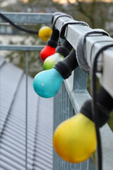 Poster - Vertical shot of frozen colorful light bulbs on metal fence