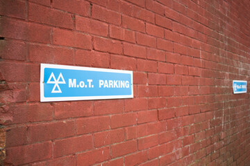 Wall Mural - sign text of uk mot testing sign on a brick red wall out doors