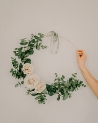 Poster - Vertical shot of a hand holding a round wedding wreath decoration