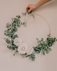 Wall Mural - Vertical shot of a hand holding a round wedding wreath decoration