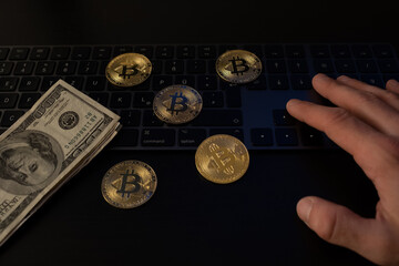 Wall Mural - Man's hand on a keyboard with bitcoins and dollar bills on top