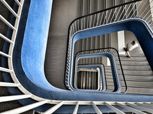 High Angle Shot Of A Person Going Down A Spiraling Blue Staircase