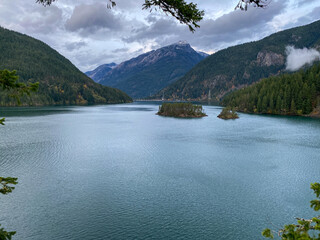 Poster - Scenic view of a blue lake surrounded by high mountains on cloudy sky background