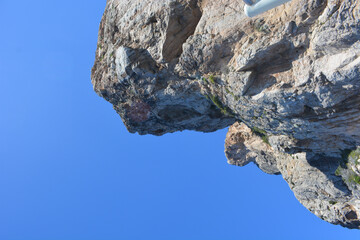 Canvas Print - Low-angle shot of the peak of a rock or cliff against the clear blue sky in summer