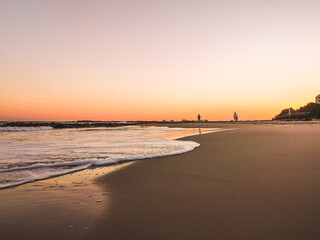 Poster - Beautiful scenery of waves on the shore with people behind during sunset