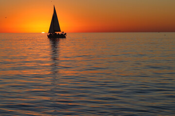 Canvas Print - Silhouette of the sailboat against the beautiful sunset above the sea.