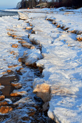 Poster - Vertical shot of frozen glaciers, stones, rocks, and land on a sea shore