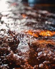 Poster - Vertical closeup shot of a raindrop falling on the ground and making a splash