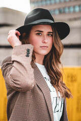 Wall Mural - Portrait of a Caucasian female with a black hat outdoors