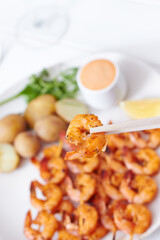 Sticker - Top view of Roasted peel prawn skewer sticks served with a sauce and vegetables on a  white plate