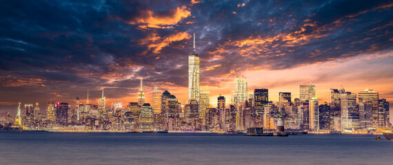 Fototapete - New York City Manhattan downtown skyline at dusk with skyscrapers illuminated over Hudson River panorama. Dramatic sunset sky.