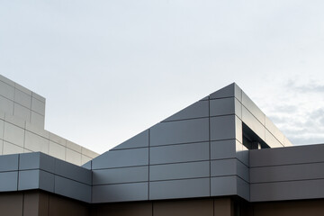 The exterior wall of a contemporary commercial style building with aluminum metal composite panels and glass windows. The futuristic building has engineered diagonal cladding steel frame panels.