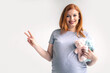© kostikovanata - Closeup young pregnant woman hugging two bear toys on huge belly posing isolated on white studio