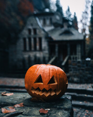 Wall Mural - Vertical shot of a jack-o-lantern against a spooky house - Halloween theme