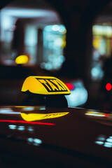 Poster - Shallow focus vertical shot of a taxi sign of a taxi car in a city at night