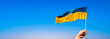 Ukrainian flag with female hand. Banner with blue sky