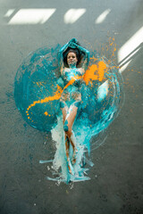 Wall Mural - bodypainting woman, expressive sexy young elegant on the floor in turquoise, blue and orange color abstractly painted, surrounded by light spots, abstract body art painting