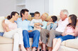 © Stigur/peopleimages.com - Three generations gather happily together. Three generations of family sitting together affectionately on the lounge couch.