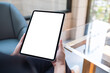 © Farknot Architect - Mockup image of a woman holding digital tablet with blank white desktop screen in cafe