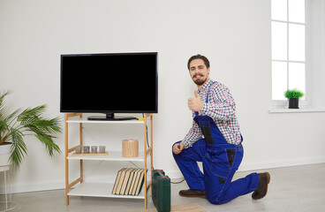 TV installation and connection service. Portrait of professional male technician who repairs, maintains and connects TV. Repairman shows thumb on camera which guarantees high quality of its work.