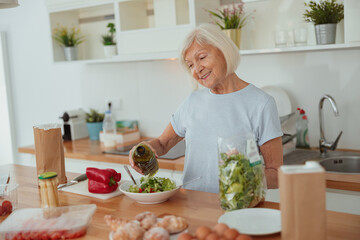 Pension age good looking woman eating green salad indoors