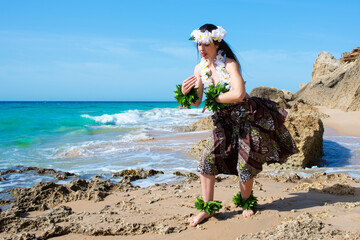 Wall Mural - Hawaiian woman enjoys hula dancing on the beach barefoot wearing traditional costume