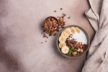 Wall Mural - Healthy breakfast of granola with fresh banana, nuts, chocolate drops and yogurt