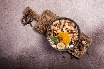 Wall Mural - Healthy breakfast of granola with nuts, banana, orange and yogurt