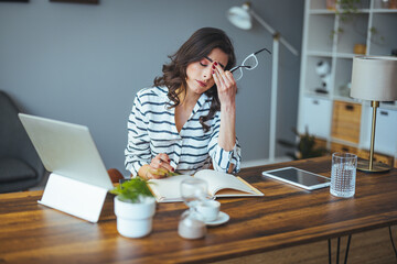 Shot of a young woman suffering from stress while using a computer at her work desk. Shot of a mature businesswoman looking stressed out while working on a laptop in an office