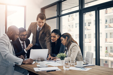 Wall Mural - work together, get more done together. shot of a group of young businesspeople using a laptop togeth