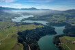 Aerial view of the Lac de la Gruyere, a lake in the canton of Fribourg, Switzerland. The lake winds through the hills of the region and is surrounded by a layer of trees.
