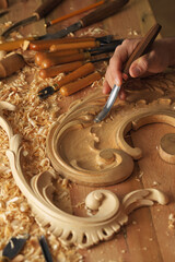 Wall Mural - Craftsman carving with a gouge. Woodwork. Workbench with equipment. Wood carving tools. Chisels for carving