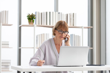 Wall Mural - senior businesswoman or freelance using laptop computer and talking about work on phone