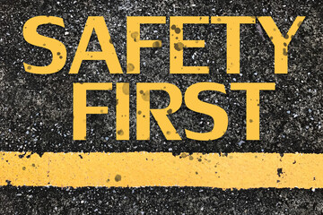 Safety first word on road grunge background.