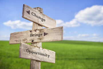 Wall Mural - Change brings opportunity text quote on wooden signpost outdoors on green field with blue sky.