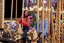 Two Smiling Young Women Ride On A Carousel