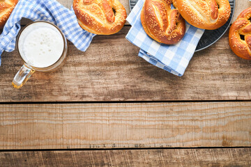 Wall Mural - Bavarian pretzels and glass of lager beer. Oktoberfest food menu, traditional salted pretzels over old wooden background. Top view with space for text. Oktoberfest theme