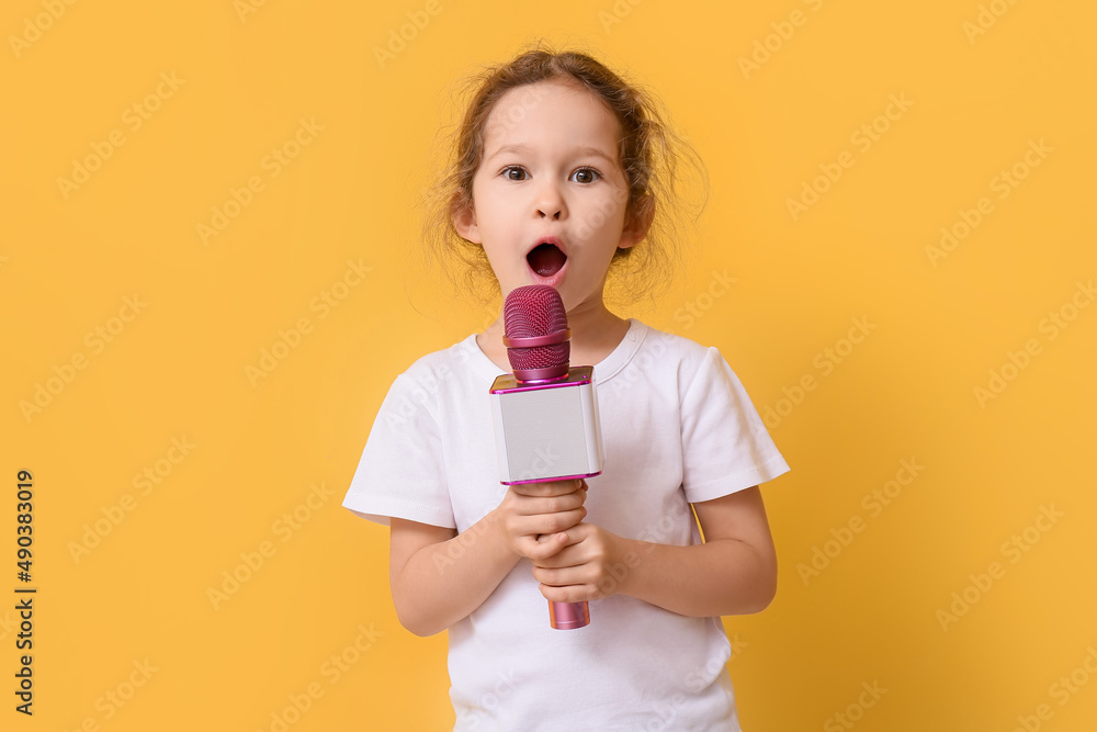 Singing cute little girl with microphone on color background