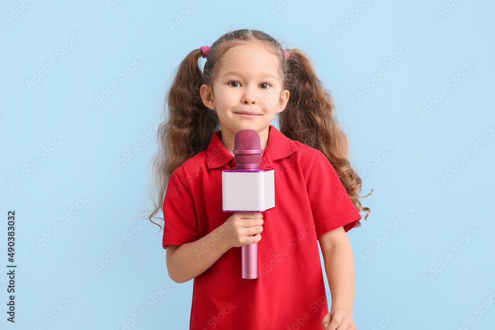 Cute little girl with microphone on color background