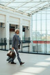 © Tijana - Smiling Business Man Holding Passport and Walking with Suitcase at the Airport