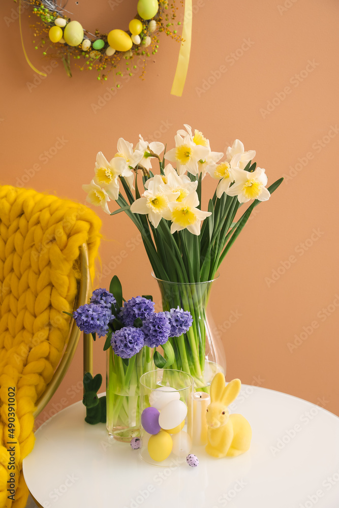 Easter decor and beautiful flowers on table near color wall