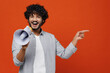 Young bearded Indian man 20s wears blue shirt hold scream in megaphone announces discounts sale Hurry up point on workspace area copy space mock up isolated on plain orange background studio portrait.