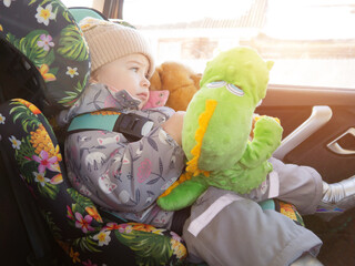 child in a child seat with toys in the car. concept of transporting children