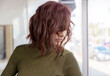 © SuperStock - Red headed middle-aged woman looks down covering her face with her hair.